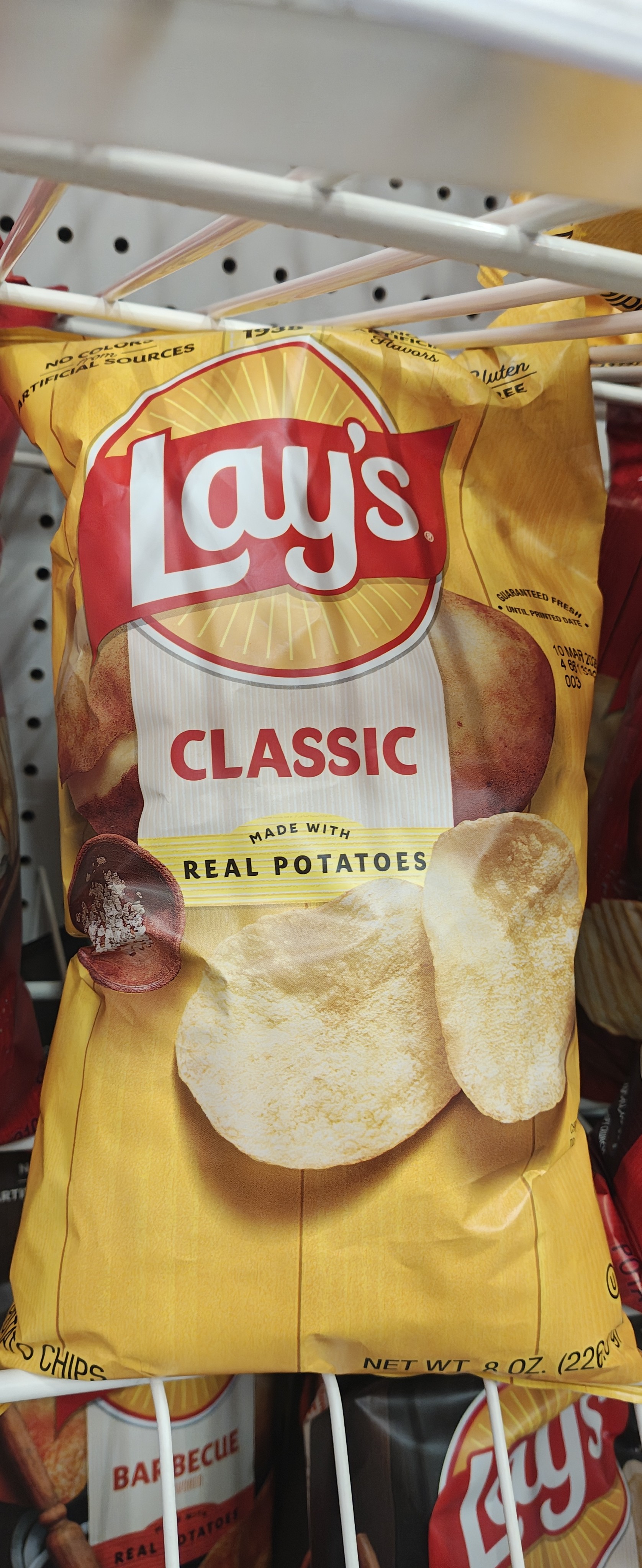 一张摆在货架上的乐事（Lay's）经典原味（Classic）薯片包装照片。包装袋为标志性的黄色，中间印有乐事 Logo 和切片薯片的图案，净重为 8 oz (226.8 g)。